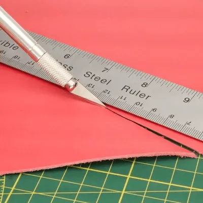 Cutting leather with precision craft knife and metal ruler