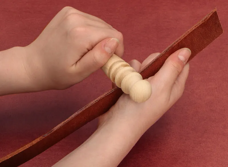 Polishing leather with wooden slicker